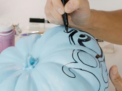 A Hand Designing a Blue Pumpkin