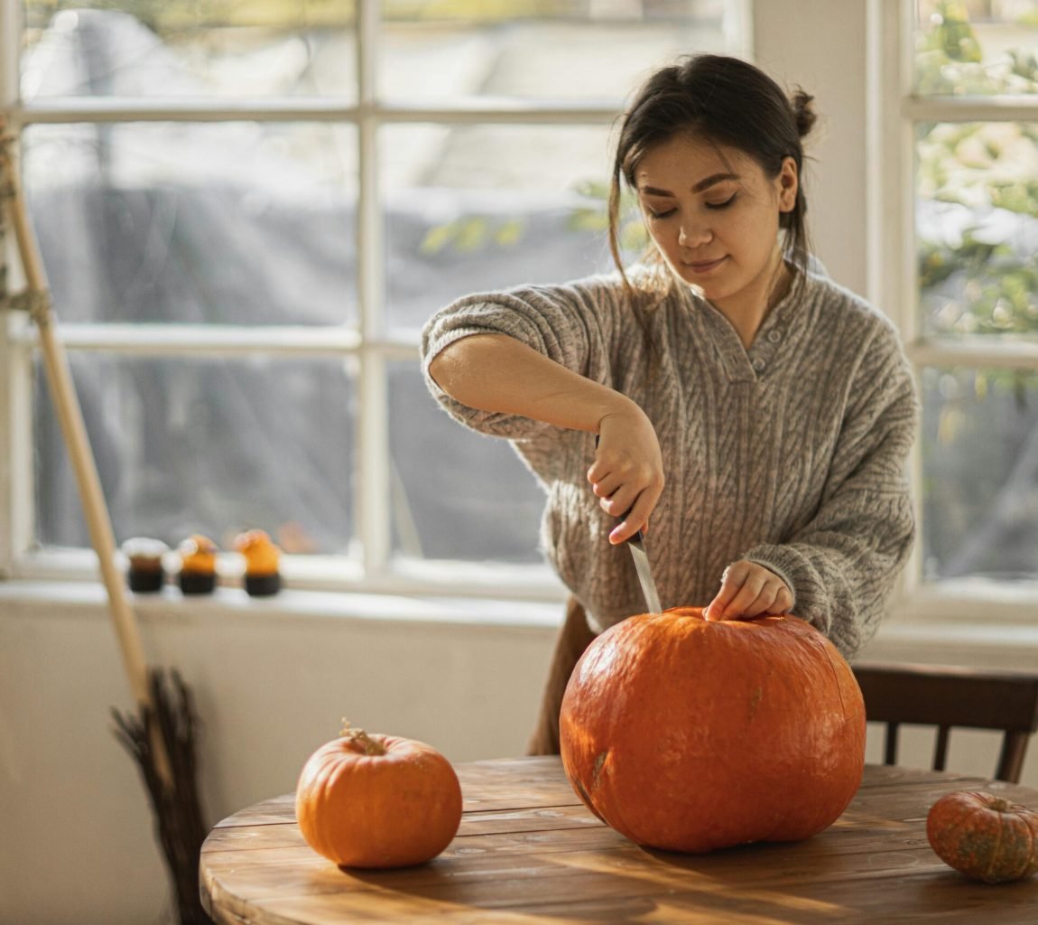 Woman in Gray Sweater Carving Orange Pumpkin