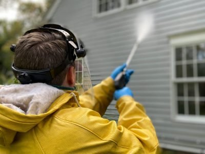 Back View of a Person Pressure Washing a House