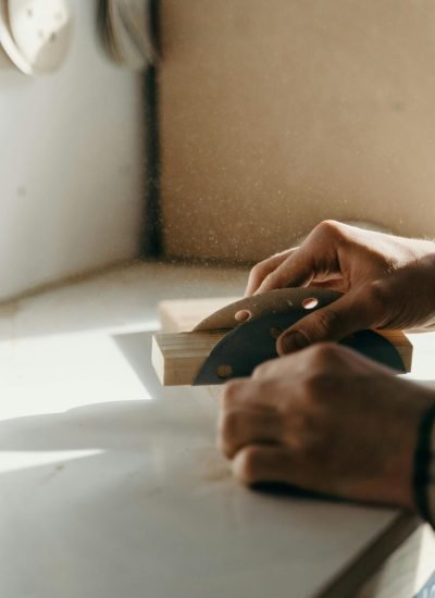 A close-up shot of hands skillfully sanding wood indoors, capturing the essence of craftsmanship.