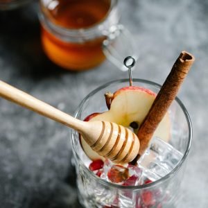 Close-up of a refreshing apple cinnamon cocktail with honey and ice cubes.